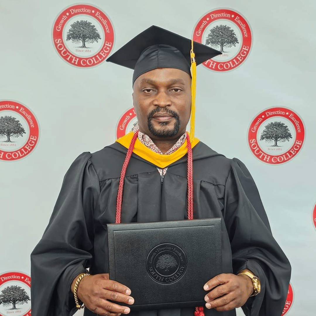 A graduate in a cap and gown stands holding a diploma. The backdrop features multiple "South College" logos with a tree emblem.